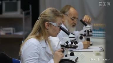 在生命科学实验室工作的卫生保健研究人员年轻的科学家和她的博士后导师正在观察显微镜载玻片